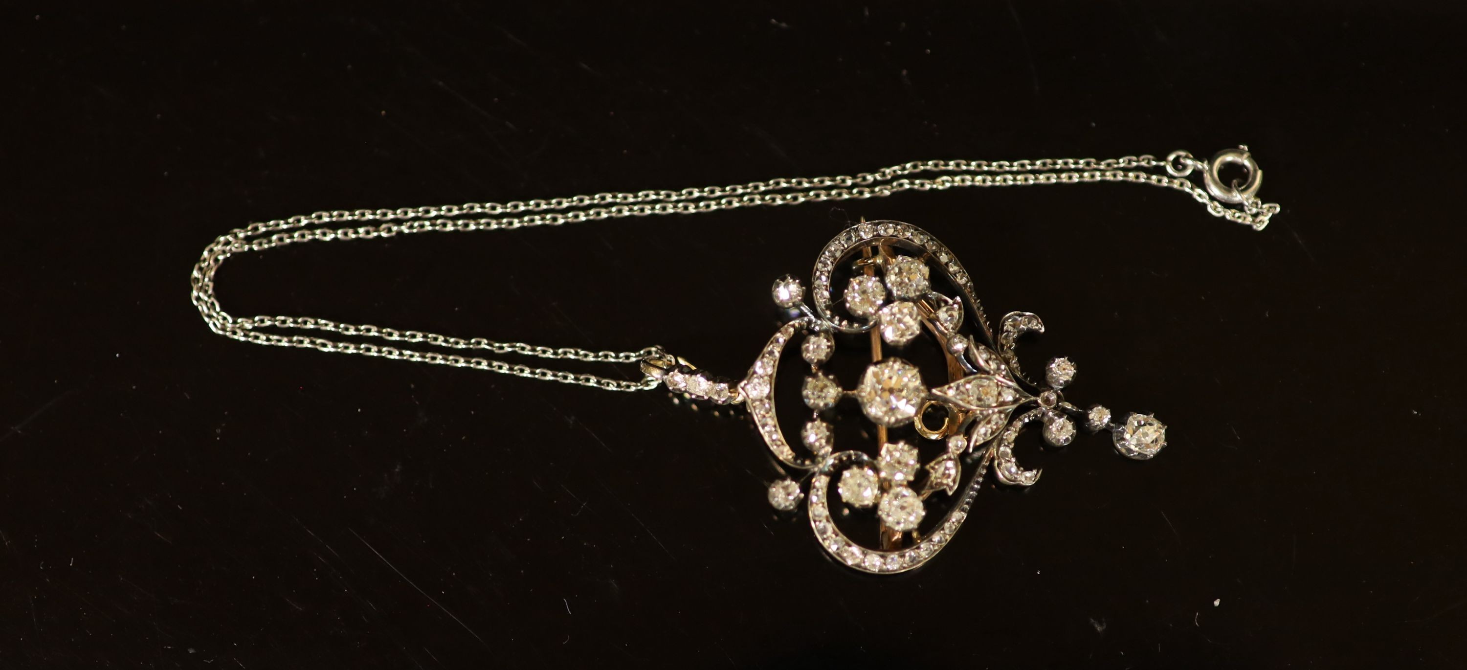 A 19th century gold, silver and diamond set open work scroll drop pendant brooch, together with a white metal chain